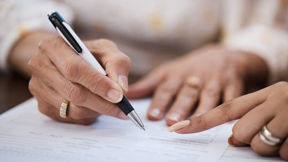 Closeup of a person with a pen signing a contract