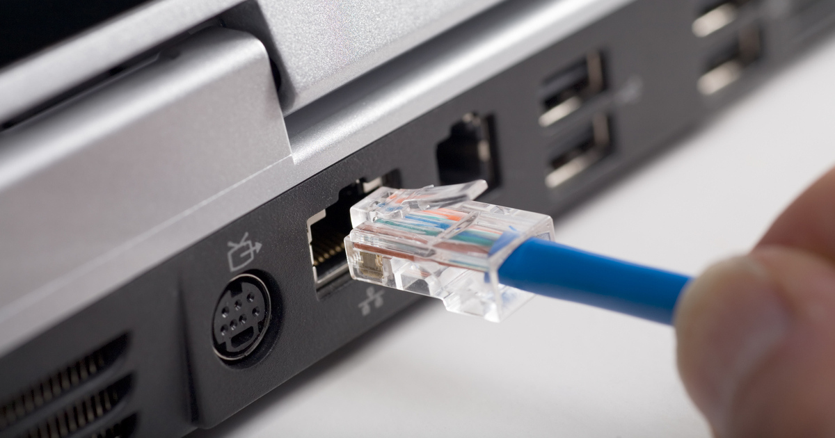 An ethernet cable being plugged into a laptop