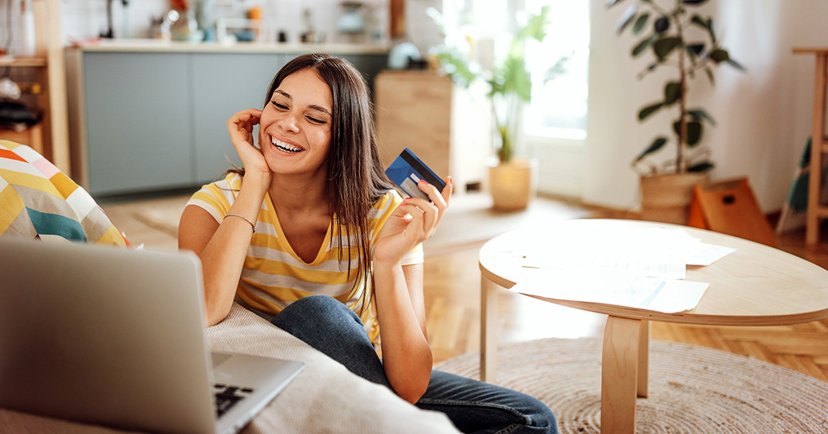Smiling woman on a laptop holding a credit card