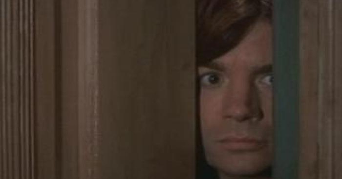 Mike Myers cautiously peeks from behind a bathroom door in a scene from So I Married an Axe Murderer.