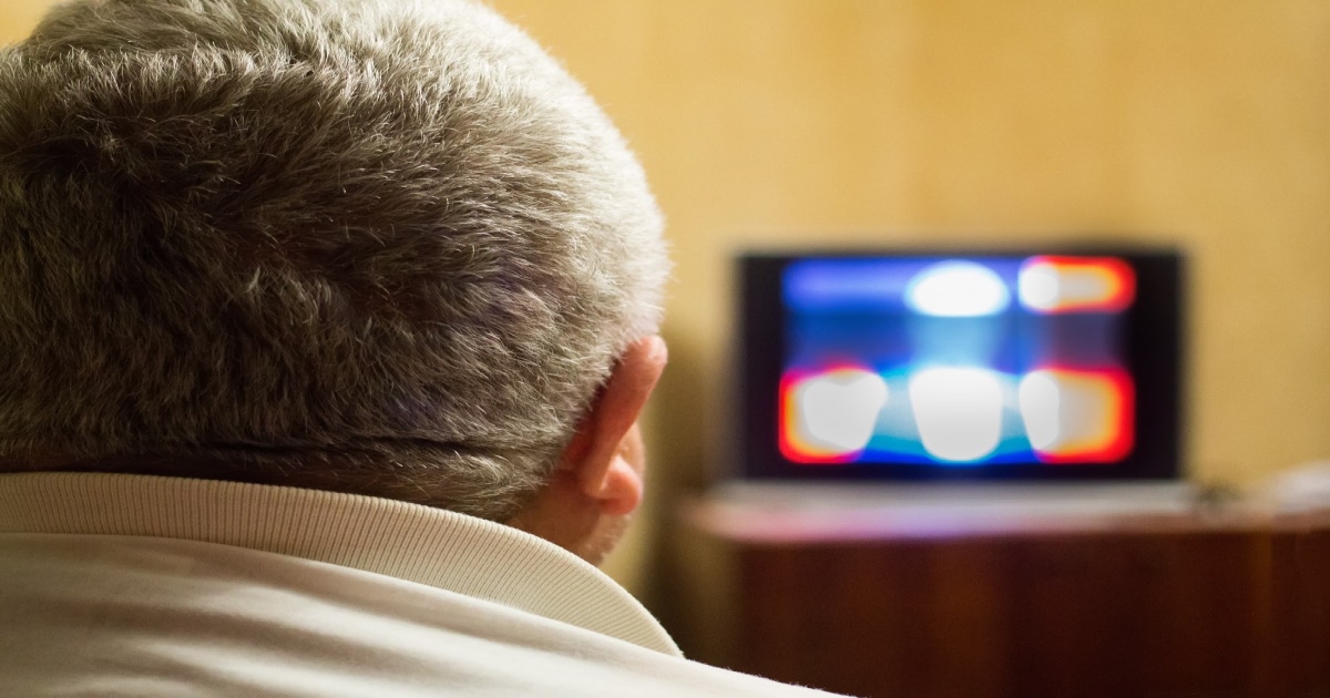 An over-the-shoulder view of a man watching TV.