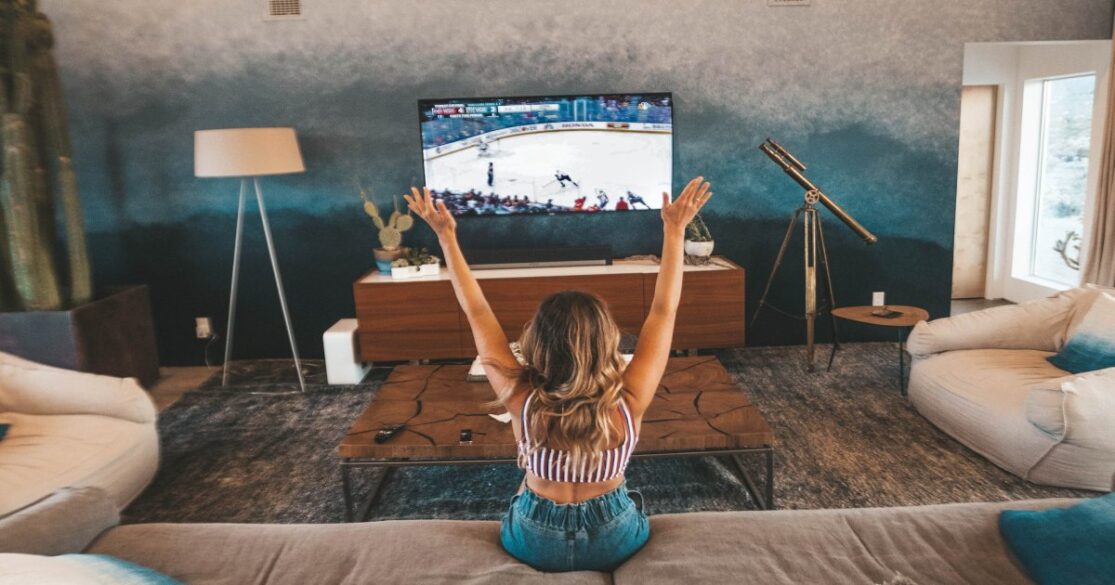 A woman celebrates while watching a televised hockey game.