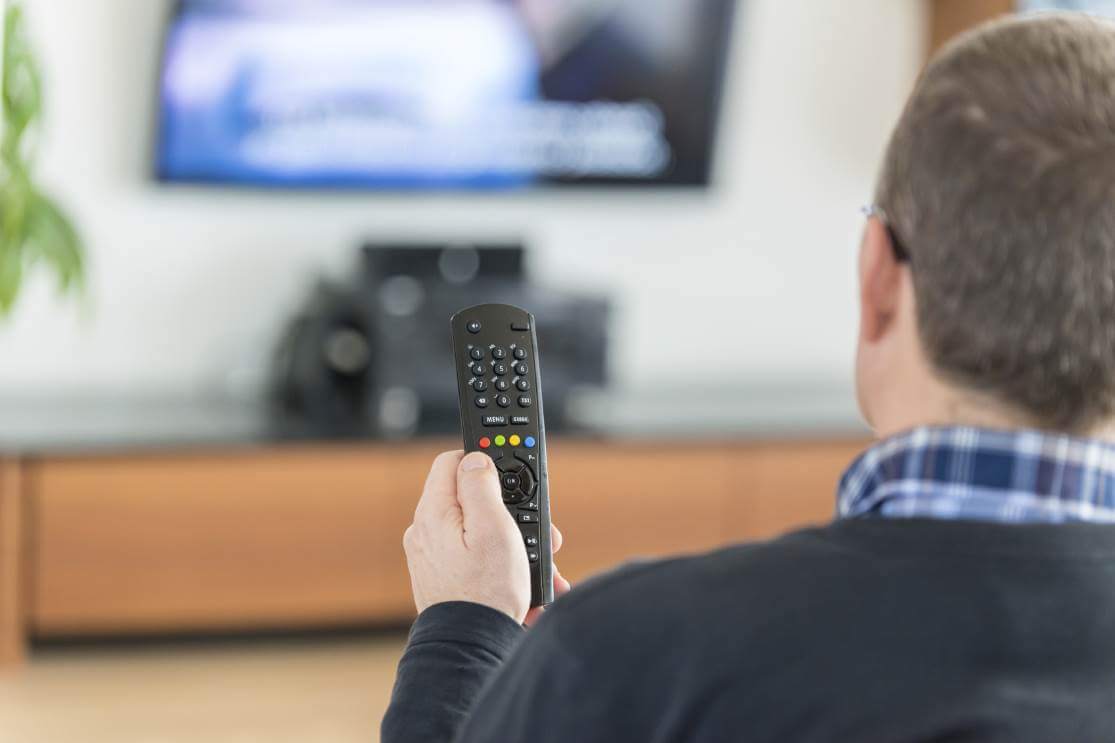 Man holding up a tv remote as he's watching television
