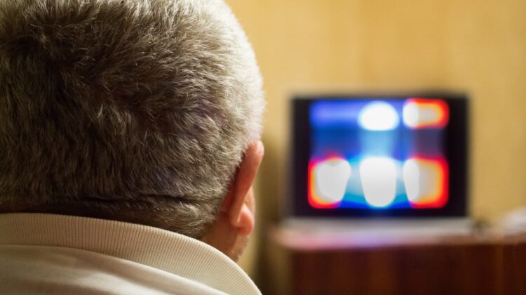An over-the-shoulder shot of a man watching TV.