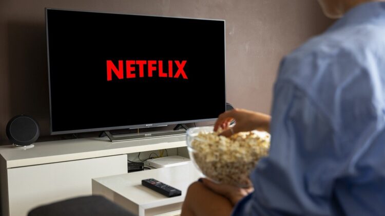 An over-the-shoulder picture of a man watching Netflix and eating popcorn