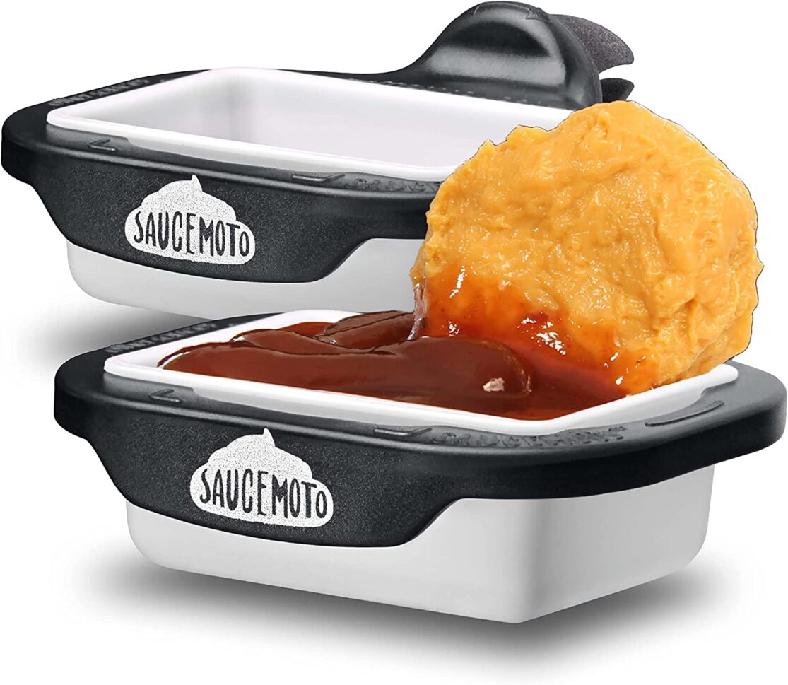 Chicken nugget being dipped into sauce container.