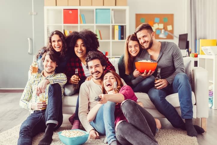 Group of friends watching tv together eating popcorn and drinking beer