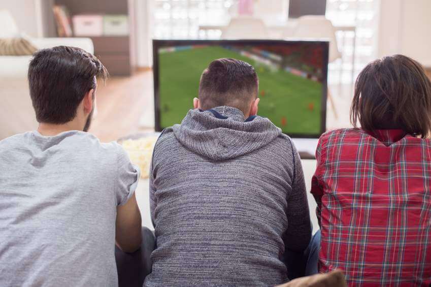Three men watching soccer on television