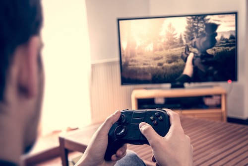 A man holding a video game controller playing a game on his TV.