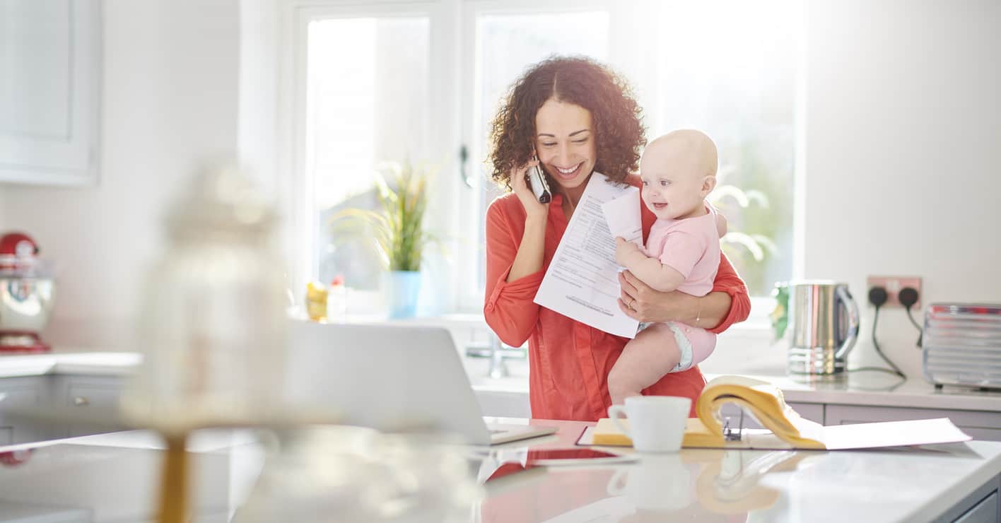woman holding baby taking on the phone holding a bill